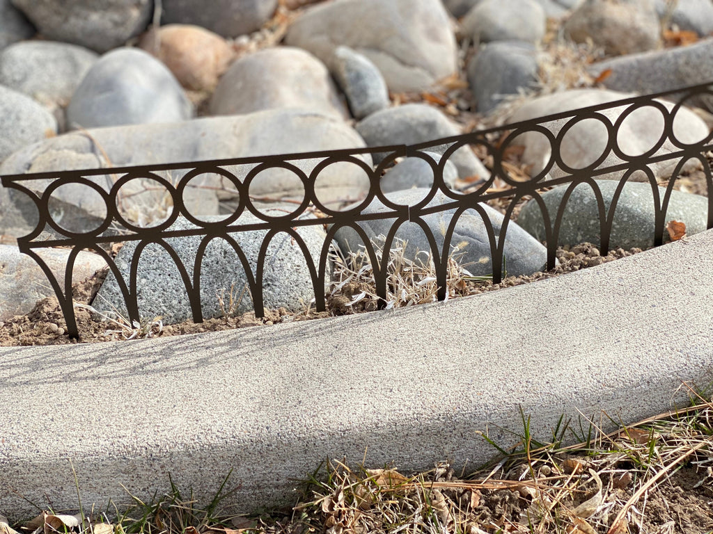 Black powder coated metal garden fence panel featuring Gothic pointed arches and decorative scrollwork with integrated ground stakes