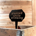 Set of three humorous metal garden markers featuring vintage-style sign board designs with funny gardening sayings, available in black, bronze, or raw steel finishes.