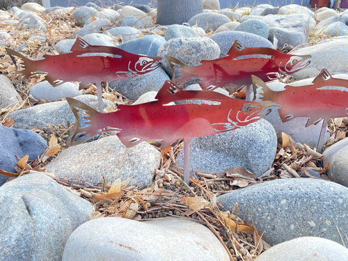 Red metal fish sculptures on a rocky surface